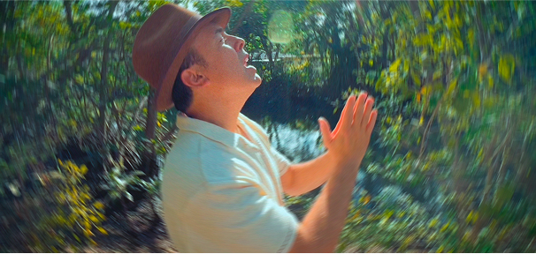 Julio Csear cantando con el fondo de arboles y naturaleza
